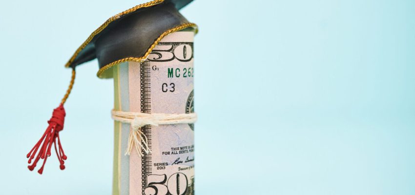 Cost of Education. Money roll wearing a mortarboard graduation cap. Shot in studio with space for copy